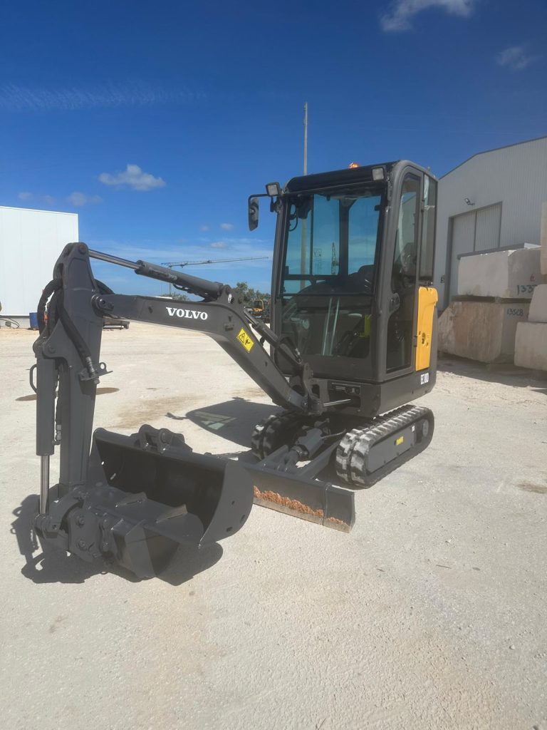 Perspetiva frontal da mini-escavadora Volvo EC18D com o balde de escavação em primeiro plano