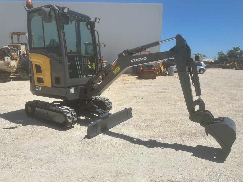 Perfil esquerdo da mini-escavadora compacta Volvo EC18D mostrando a lâmina niveladora e os rastos